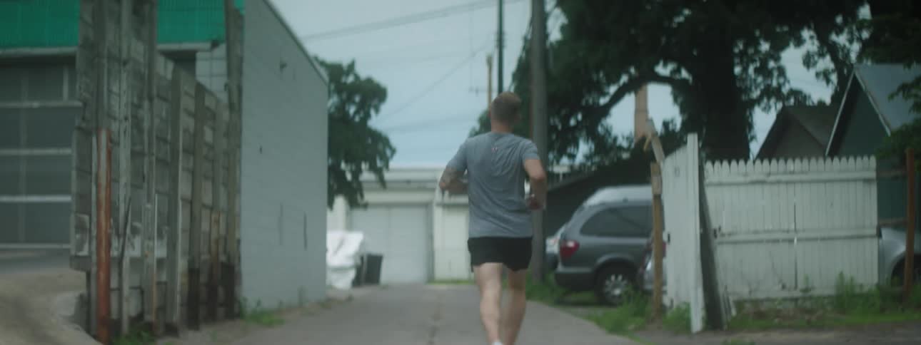Man in athletic clothing runs down alley in neighborhood