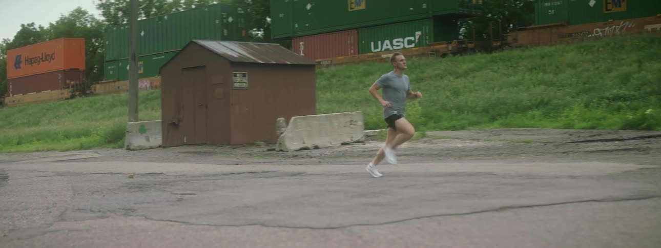A man runs through a parking lot alongside a train