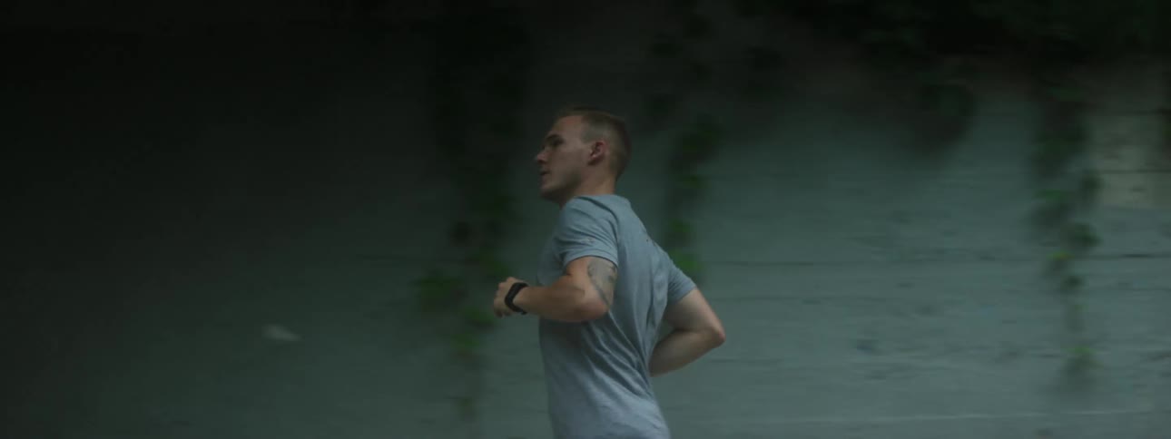 A man jogs beneath an overpass on a summer day