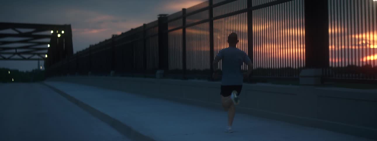 A man running on a bridge with the sky in the background