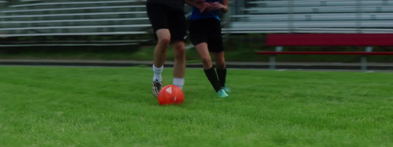 A female soccer player attempting and succeeding in stealing the soccer ball from a male player