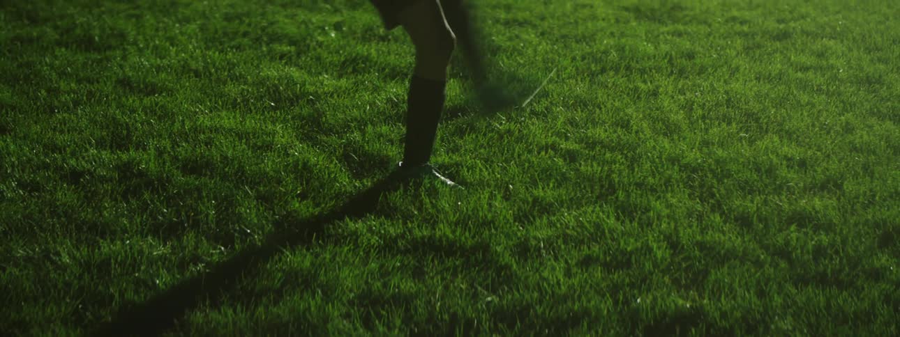A female soccer playing doing kicking drills on a soccer field at night