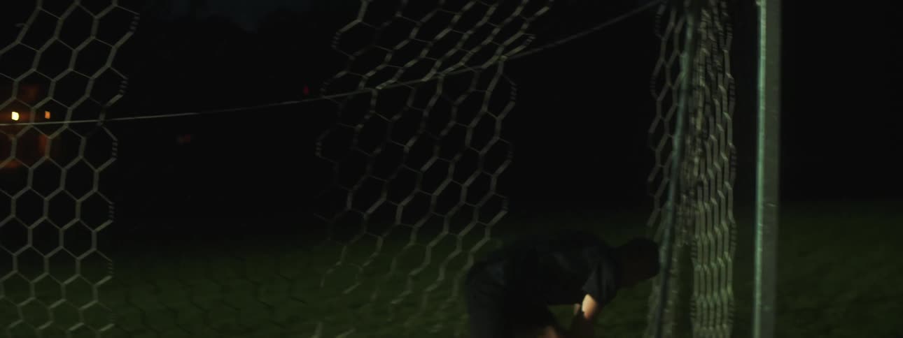 A man catches the ball and throws it back playing goalie by the net