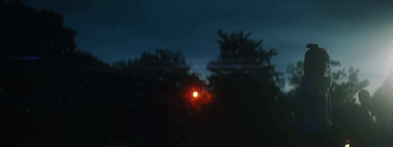 A man and woman talk outside at night