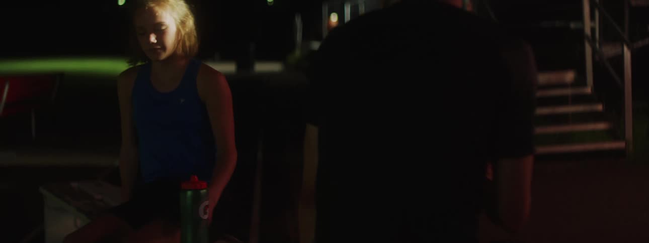 Teenagers take seats on bench in park at night