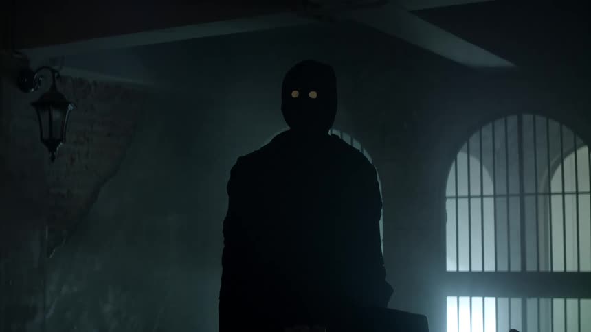 A person dressed in a costume with a mask stands still