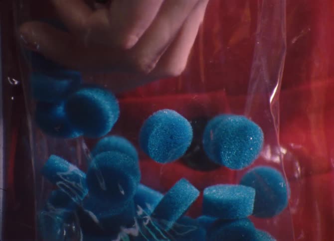 A woman reaches in to a bag and grabs some little sponges