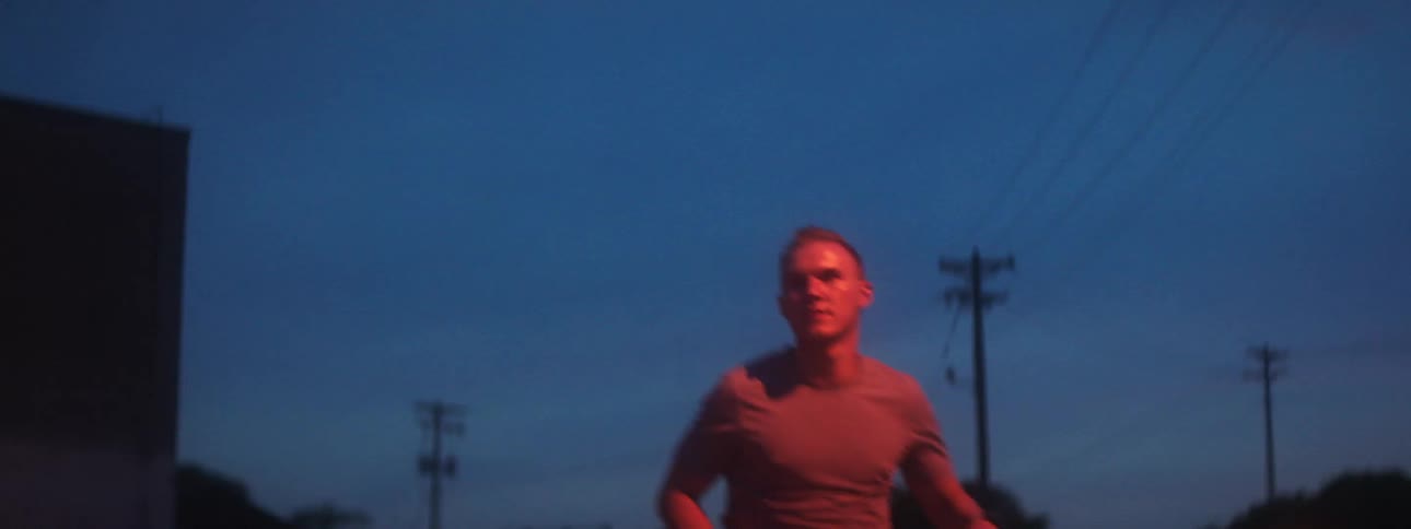A man jogs in a residential neighborhood under street lights