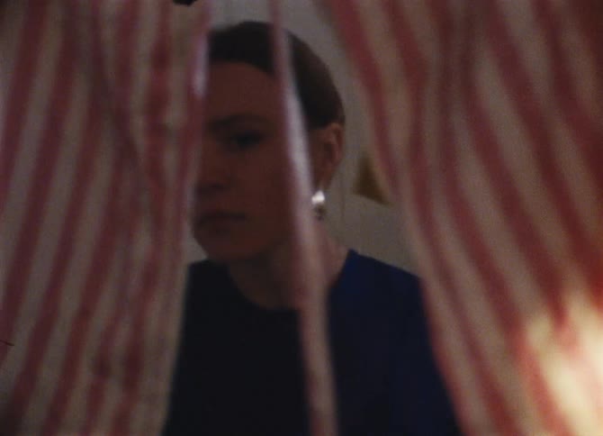 A young woman walks through a maze of items hanging from a ceiling