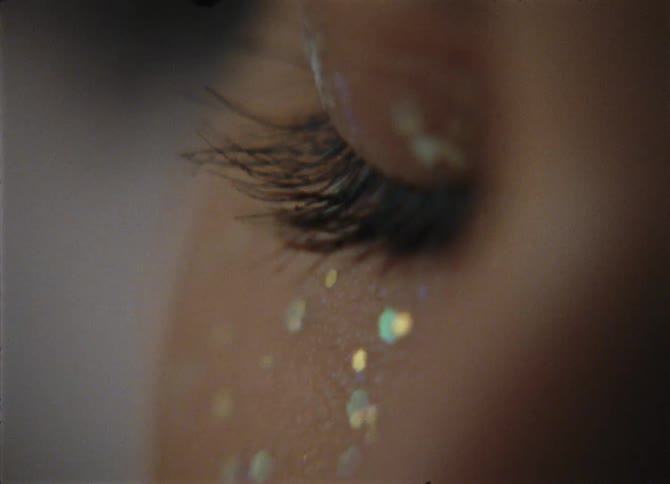 Glitter decorates cheek and eye lid of woman
