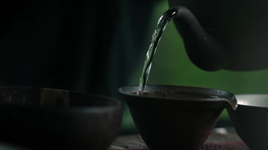 A person pouring hot water from a kettle into a cup