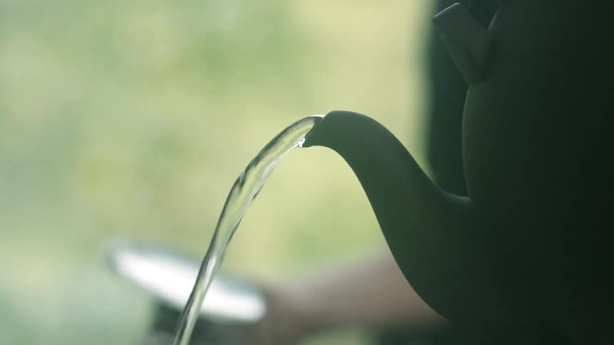 A white woman pours hot water out of a kettle