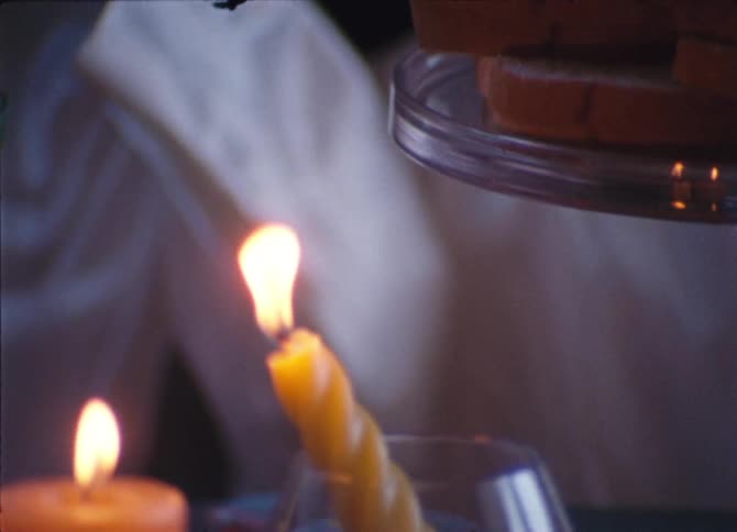 Grapes are hung over bread slices and lit candles on flat surface