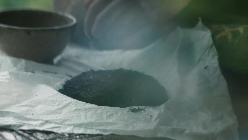 A white woman uses a knife to scrape a substance and puts it in a bowl