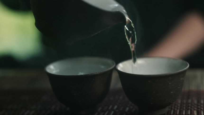 A person pouring hot water into two cups
