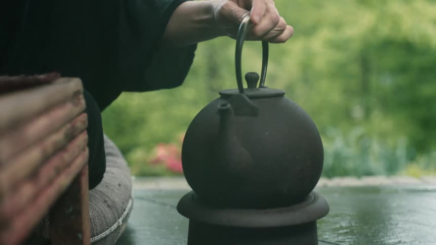 A white woman sets a kettle on a burner