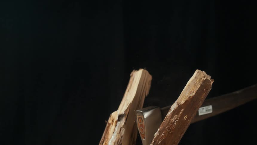 A white person swings an ax and splits a log