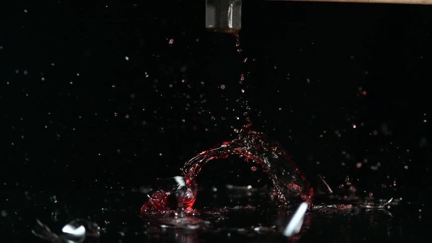 A hammer shatters a glass of wine in a studio