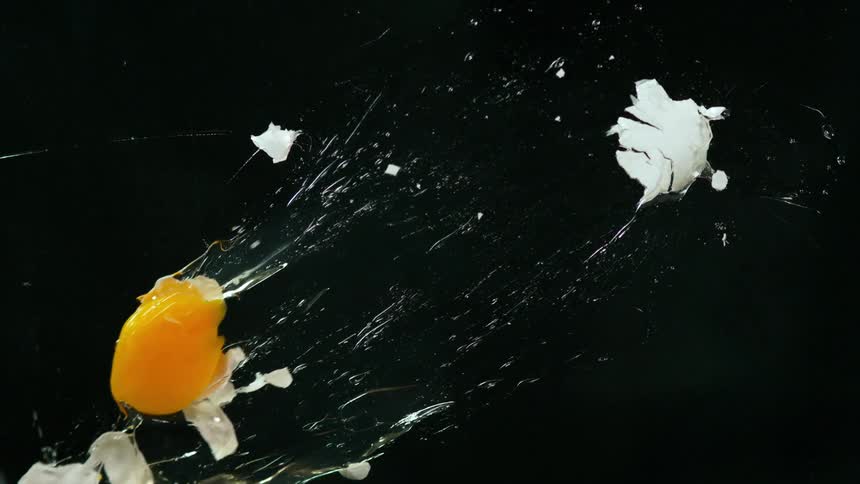 A person throws an egg in front of a back drop in a studio