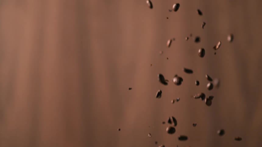 Coffee beans falling in front of a backdrop in a studio