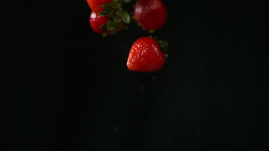 Strawberries spinning while rising through the air and out of frame