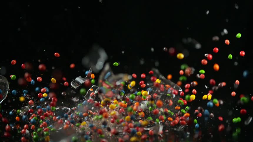 Glass jar filled with colorful candy falls down and breaks