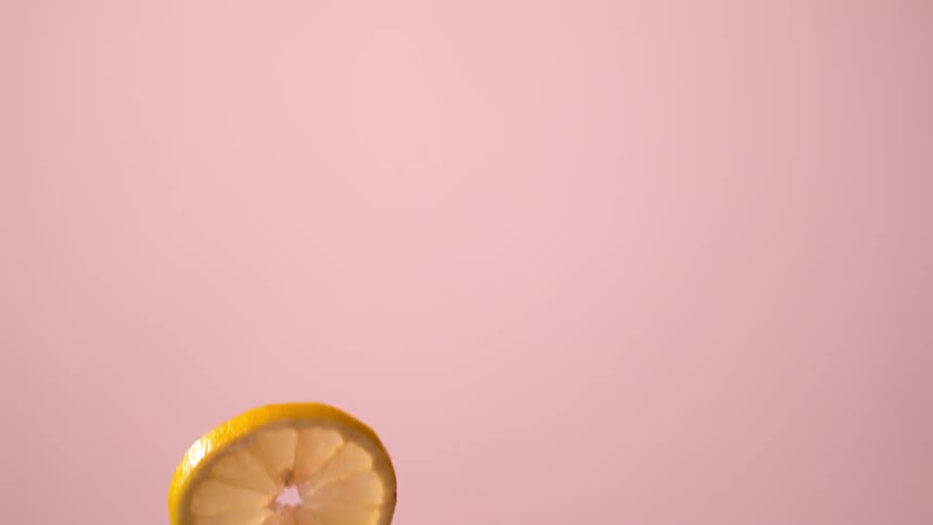 A lemon slice slowly falling in a pink room