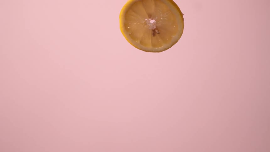 Lemon slice tossed in front of pink background