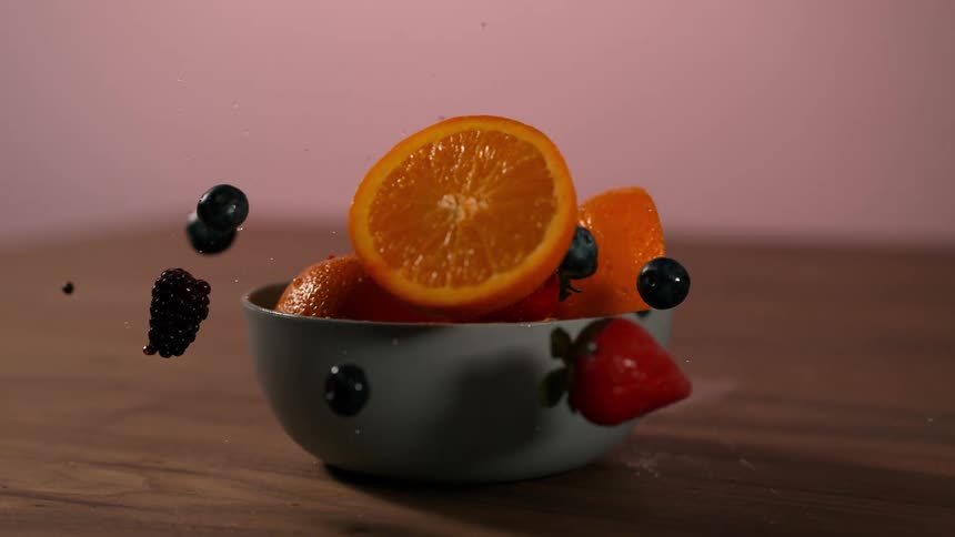 Fruit falls into bowl on table