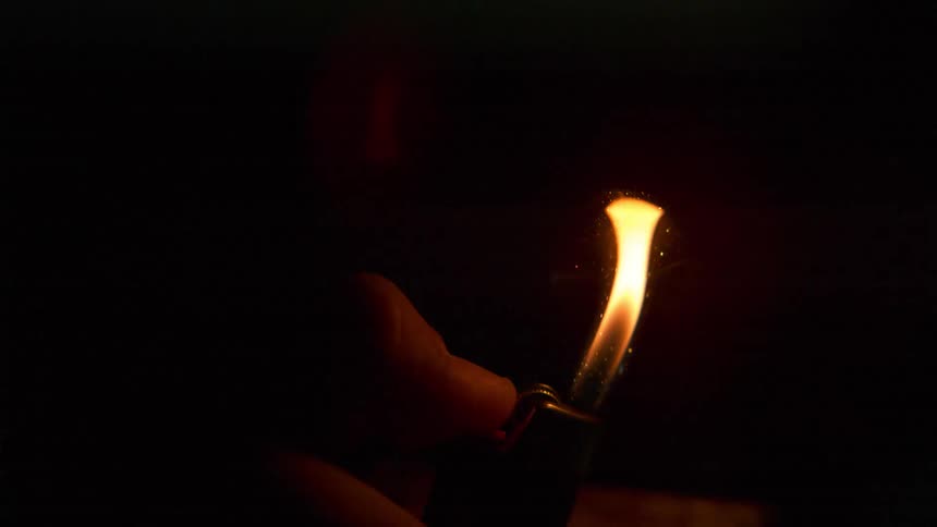 A man flicks a lighter and a flame appears