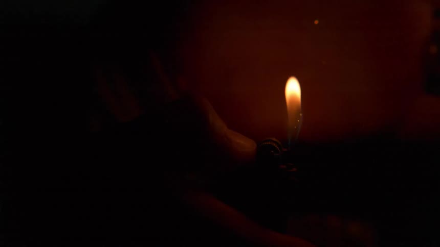 A man lights a lighter as his hand is by the flame
