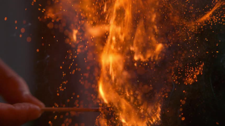 Fire and flames around fingers holding a wooden match