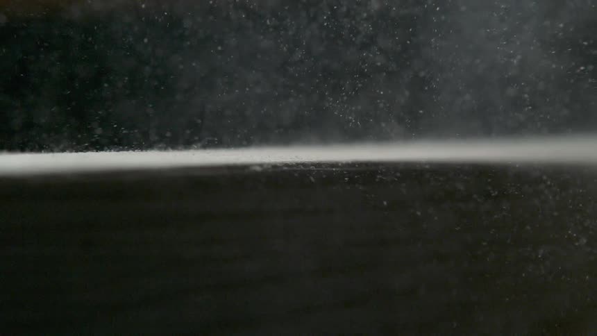 Dust blows off of a large wooden board