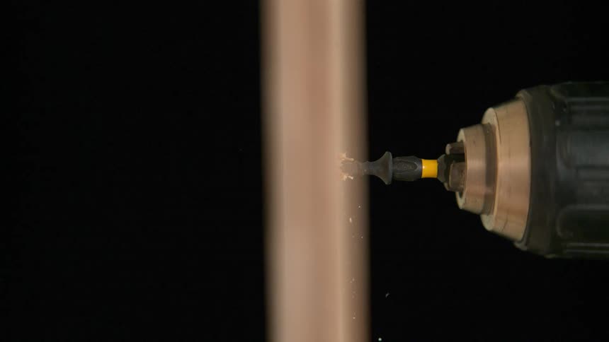 A power drill drilling a screw through wood