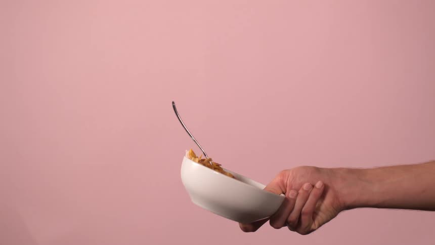 Hand tossing a bowl of cereal with milk into the air