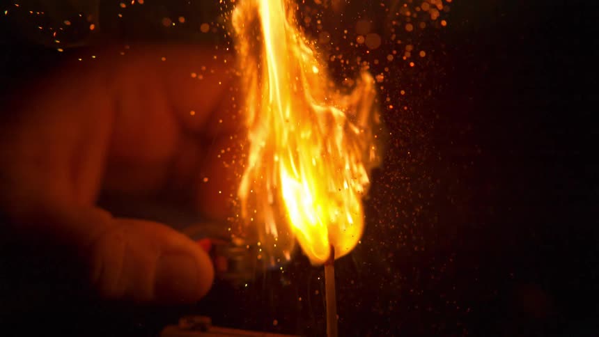 A person lights a match with a lighter