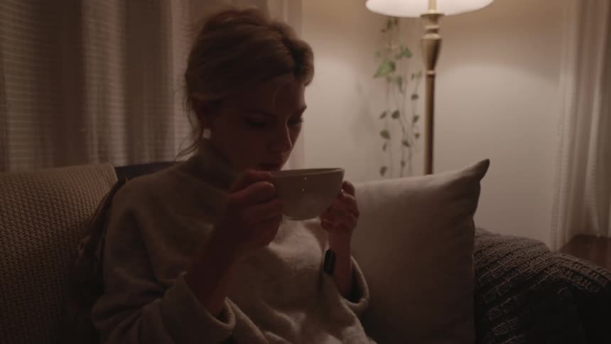 A woman checks her tea bag and takes a sip