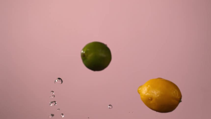 Citrus fruit falling in slow motion against pink background