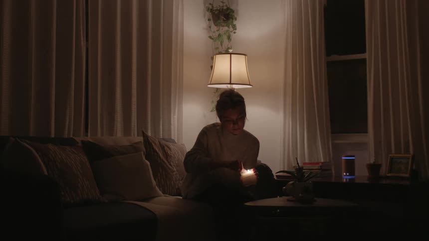 A woman picks up a candle lights it and places it back on a coffee table