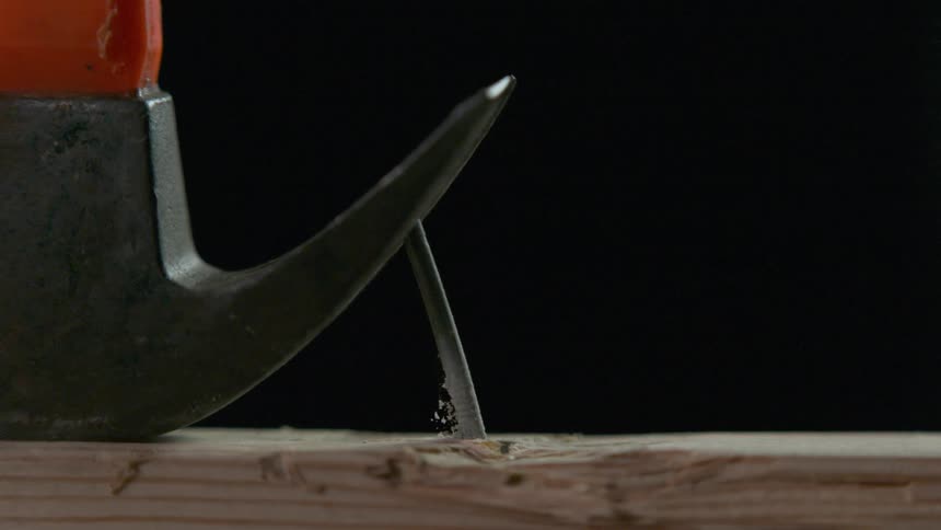 Nail being removed from a piece of wood with a hammer claw