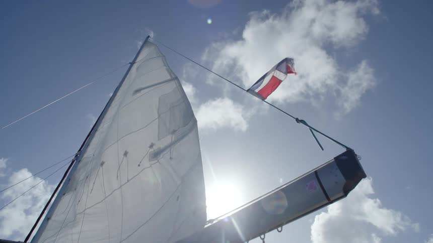 The sail of a boat flaps in the wind