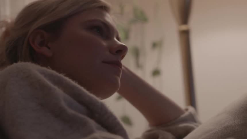 Woman sitting on couch watches television at home