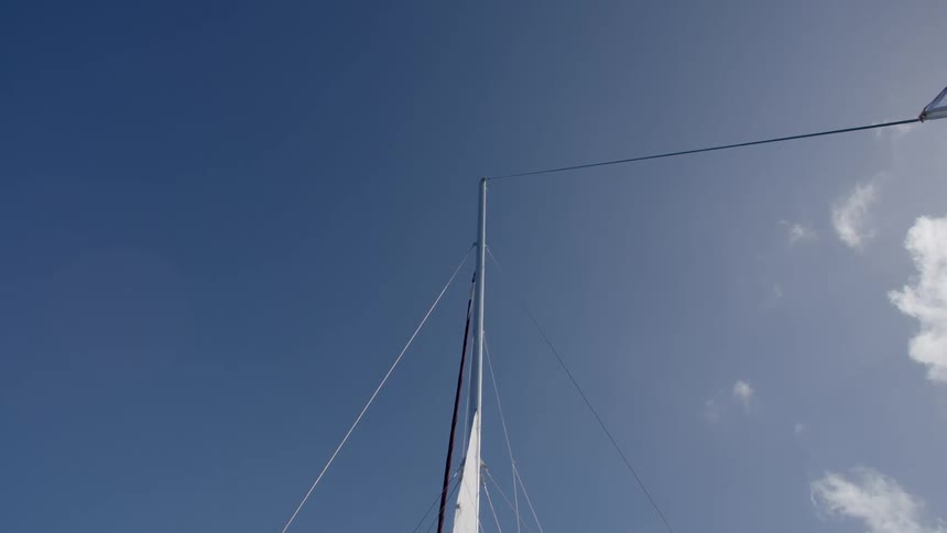 Flag waves on line from boat mast against blue sky