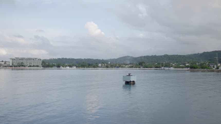 A mountain range sits behind a neighborhood next to a vast ocean