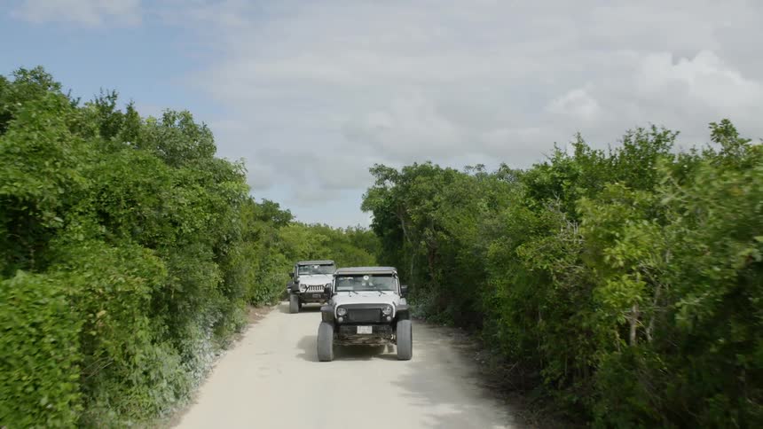 Two jeeps driving down a dirt road