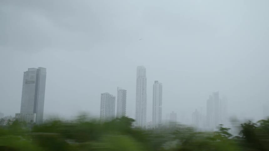 The skyscrapers of a metropolis looming in the fog under a cloudy sky