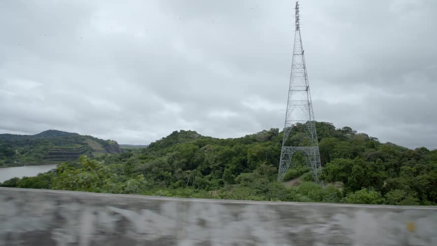 An electrical tower next to a lake