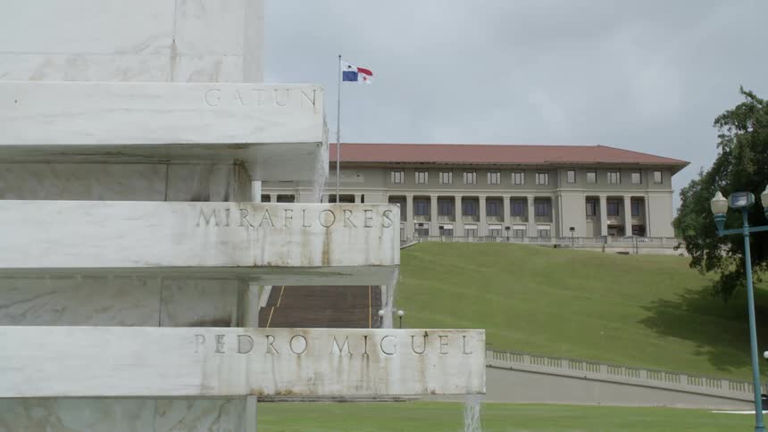 The flag of panama flies in front of the visitor center behind the flowing water of the goethals monument