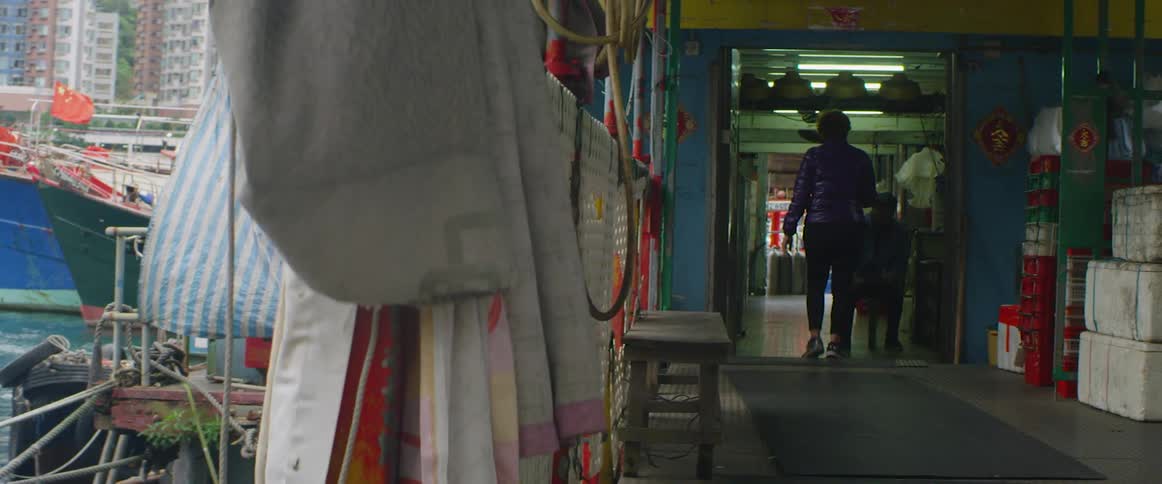 Woman walks down a hallway near some hanging pieces of fabric