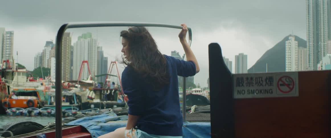 Young woman riding on small ferry boat in front of city skyline